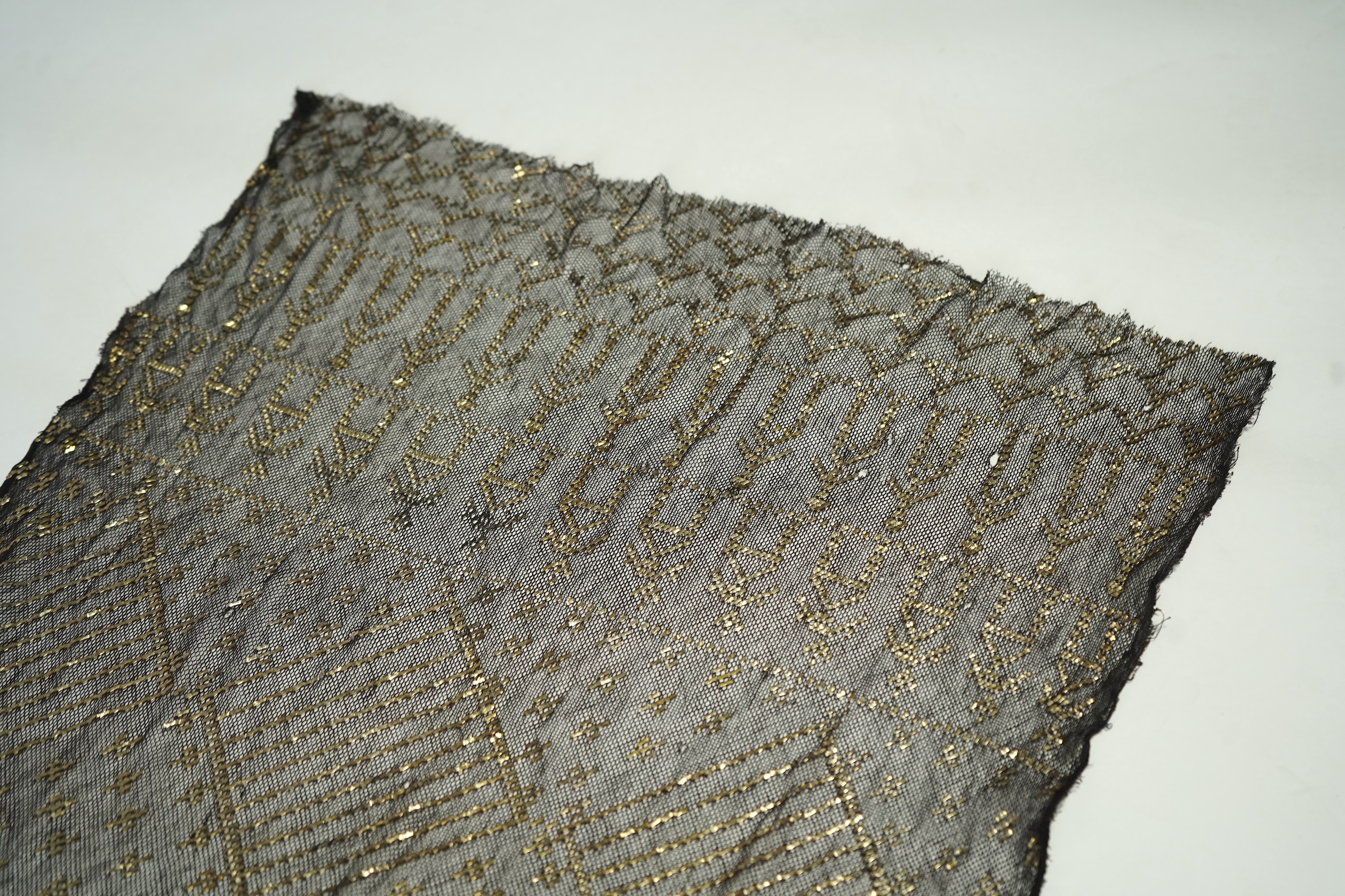A 1930’s Egyptian decorative metal on black net evening stole. Approximately 218cm long. Condition - the rolled edges are frayed but the colour and design are intact.